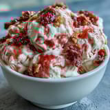 Greek yogurt swirls with strawberry flavor, topped with crunchy banana chips for a refreshing frozen treat.