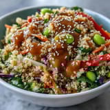 A vibrant Thai coconut quinoa bowl with crunchy vegetables, edamame, and a rich peanut dressing for a healthy, flavorful meal.  