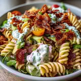 Creamy BLT pasta salad with crispy bacon, ripe avocado, and fresh tomatoes in a tangy dressing.
