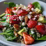 Colorful quinoa salad bursting with strawberries, avocado, and fresh greens, topped with toasted nuts for a satisfying gluten-free side dish.  