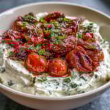 Velvety feta cheese dip blended smooth and topped with sweet, caramelized roasted cherry tomatoes—perfect party snack.  