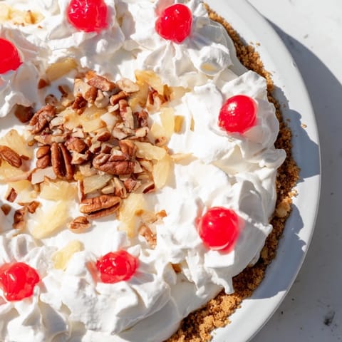 Cool, refreshing Millionaire Pie, its sweet, creamy filling topped with vibrant red cherries and nuts.