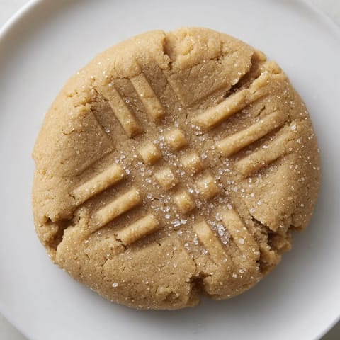 Fork-marked peanut butter cookies, fresh from the oven, offering a classic chewy texture.