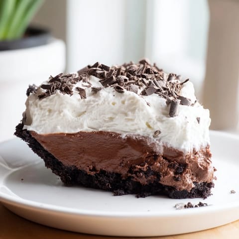 A slice of Mississippi Mud Pie, showcasing a fudgy brownie base and creamy chocolate pudding.