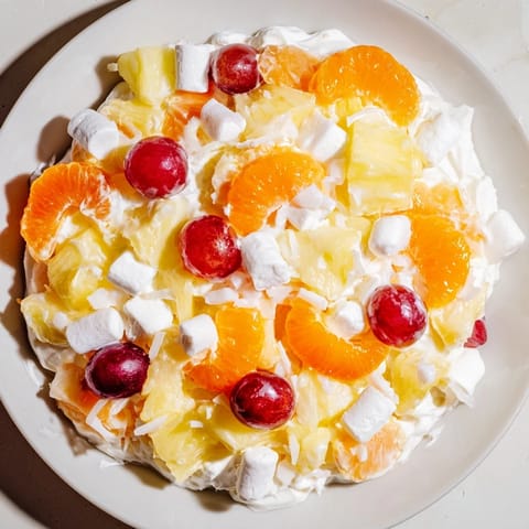 A vibrant, creamy bowl of Ambrosia Salad features mandarin oranges and fluffy marshmallows.
