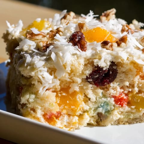 Warm, frosted fruit cocktail cake, with visible pieces of fruit ready to enjoy as dessert.