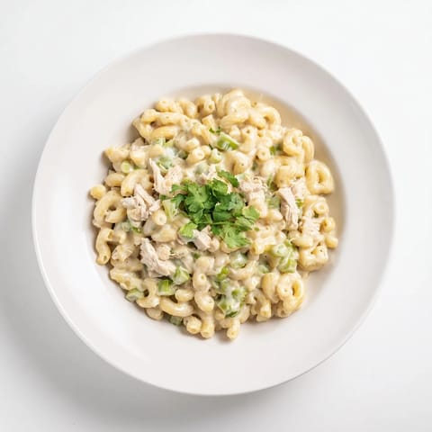 A close-up of creamy Green Chili Chicken Mac in a cast-iron skillet, with melted cheese stretching from a serving spoon.