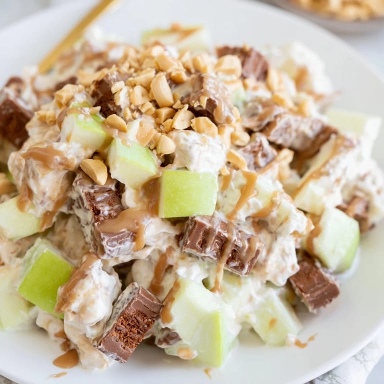 Close-up of vibrant Snickers Salad showcasing chunks of candy and crisp apples in a creamy base.