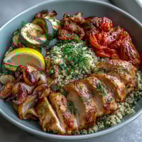 A vibrant paprika herb chicken bowl with roasted vegetables and quinoa, drizzled with rose harissa for a fragrant, flavorful kick.  