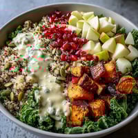 Kale Harvest Grain Bowl with quinoa, roasted sweet potatoes, and crisp apple, topped with pomegranate seeds and pepitas, drizzled with tangy maple-mustard dressing.  