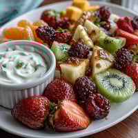 A colorful spring fruit platter with strawberries, mango, and kiwi served with creamy honey-yogurt dipping sauce.
